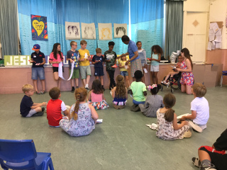 Children showing things they've made to Vicar Ola in the church hall